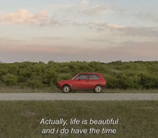 A lone red 80s car on the side of a road and the caption “actually, life is beautiful and I do have the time”